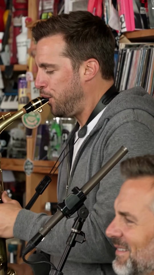 Hombre con sudadera gris tocando el saxofón